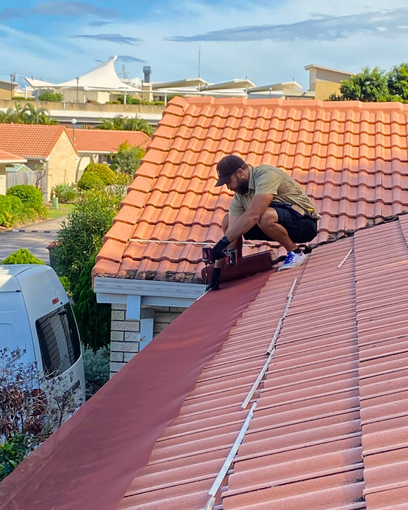 Worker installing ember guard mesh on tiled roof
