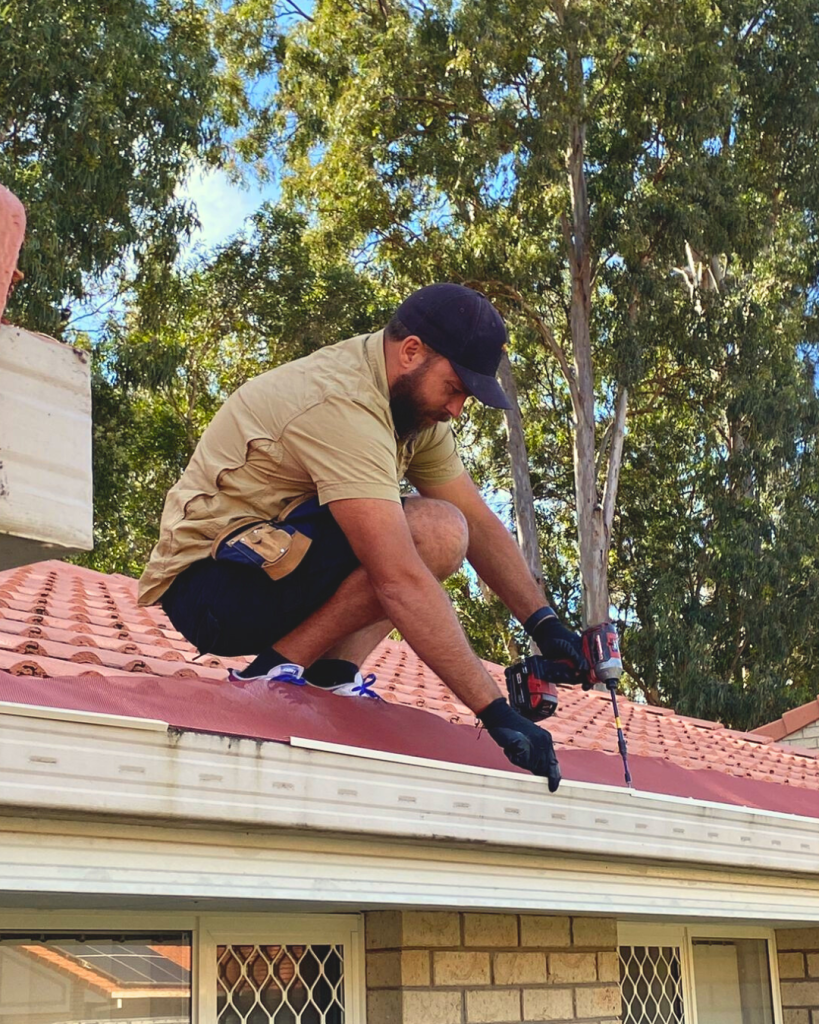 Man using drill to install ember guard on tiled roof