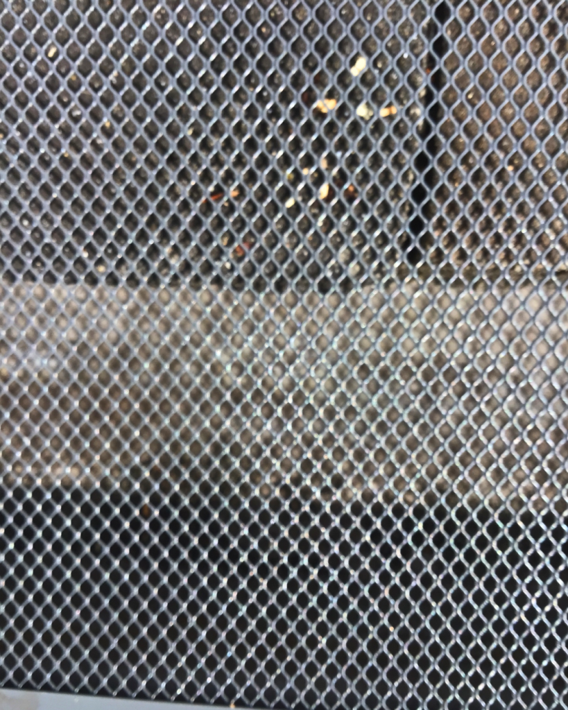 Close-up of mesh ember guard with trapped debris and seeds