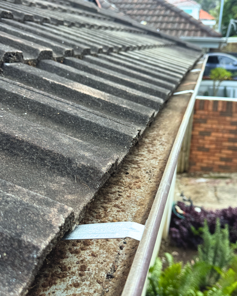 Rust-spotted gutter running along roofline with mounting brackets.