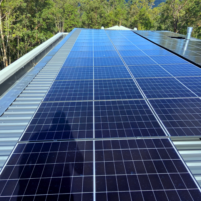 Clean, streak-free solar panels on a roof surrounded by trees.